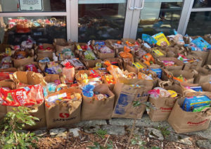 50 or so full paper grocery bags stacked outside of a food pantry