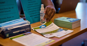 A table with flyers and resource booklets. A hand reaches in to pick up a flyer.
