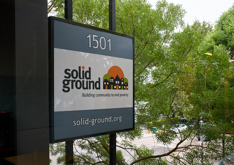 A sign on the side of a building that reads "Solid Ground - Building Community to Solve Poverty."