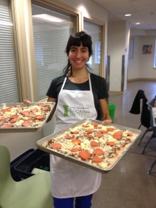 Volunteer chef, Kara, presents pizza made by class volunteers before heading to the oven.