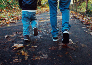 Father & son walk on a leafy path