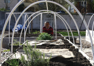 Jamari Tompkins peeks through the frame of a raised garden bed at Leschi Elementary school.