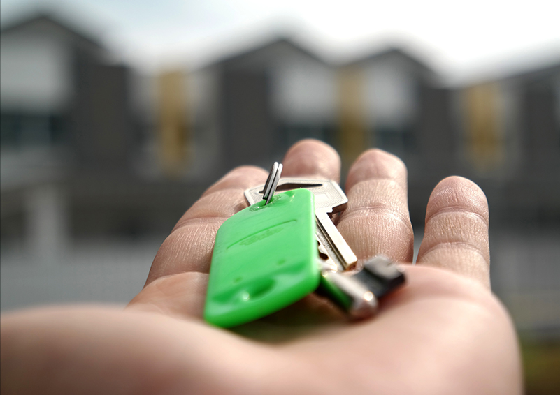 Keys in hand with housing in the background