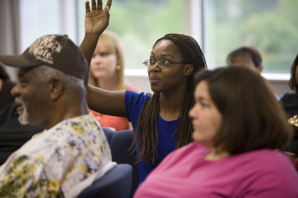 Black woman raises her hand to ask a question during a workshop