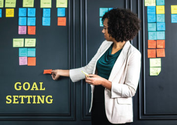 Goal Setting: Woman places multi-colored post-it notes on a visioning wall