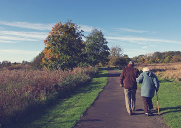 Elderly couple walk down a path
