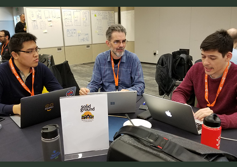 GiveCamp's Xuan Wang & Maxwell Rediker consult with Solid Ground Data Systems Developer, Joseph Boland, to finalize an emergency messaging system for Sand Point Housing residents.