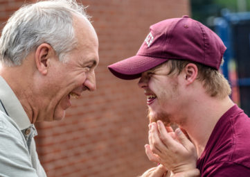 A senior man laughs with a developmentally delayed younger man