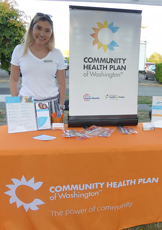 Woman stands at Community Health Plan of Washington table & display.