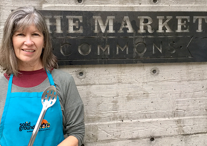 Cooking Matters volunteer Peggy Keene, wearing a teal Solid Ground apron and holding a slotted spoon