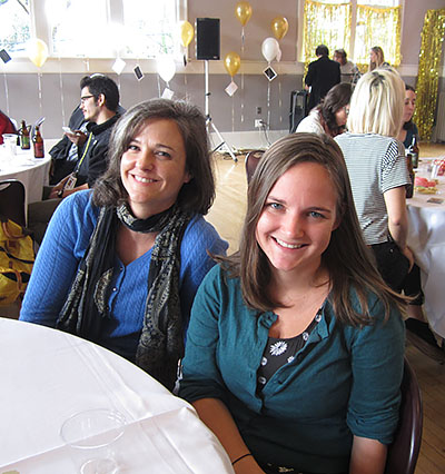 Two women smiling at a holiday party table