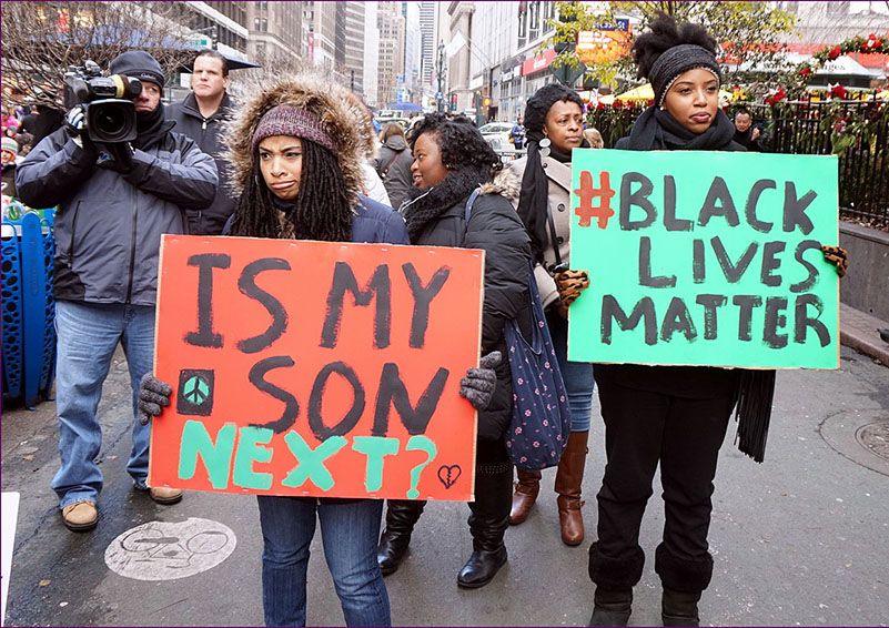 Two women at Black Lives Matters protest hold signs: Is My Son Next? & Black Lives Matter