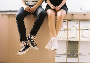 Two teens sitting on a wall.