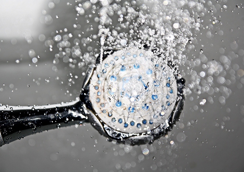 a black showerhead with water droplets pouring out