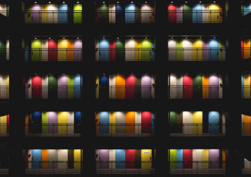 Five stories of an apartment building with brightly lit, multi-colored doors