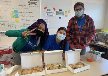 Three healthcare workers wearing masks with boxes of donated cookies