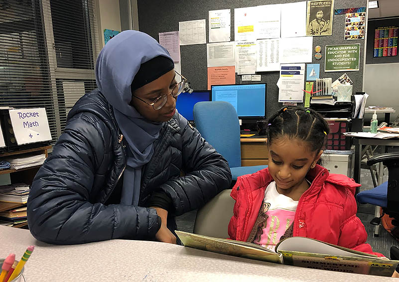 A lady tutor helping a kid read a book