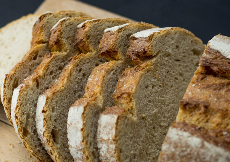 Sliced homemade whole-grain bread on a cutting board.