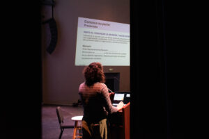 A woman speaks at a lectern (photo shot from behind).