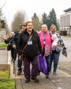 Several people smile as they lead a group down a sidewalk.