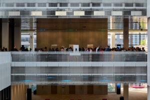 View of guests in a convention center lobby from across an opening to the floor below.