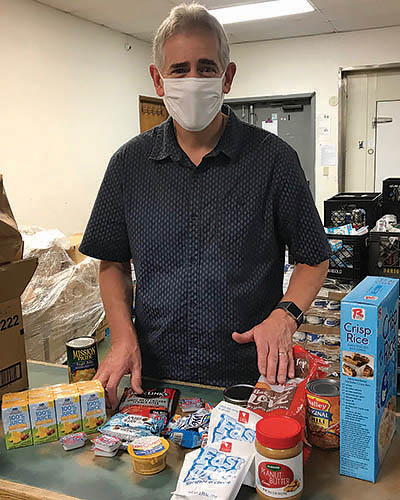 Senior male volunteer sorts food in a food pantry