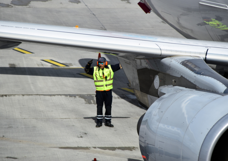 An airport worker underneath the wing of a jet.