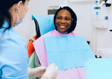 A young black woman seated in a dental chair talked with a dental health professional