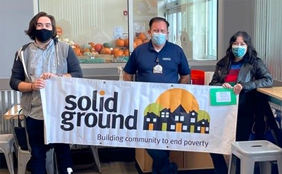 Three people holdings a banner with the Solid Ground logo