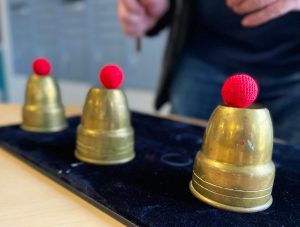 Three red balls atop brass cups.