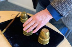 A magician's hand and three brass cups
