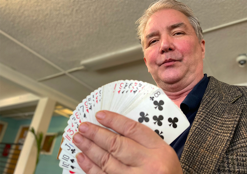 A man holds a fanned deck of cards in front of his face