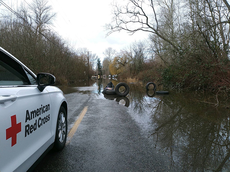 An American Red Cross vehicle faces a flooded road.