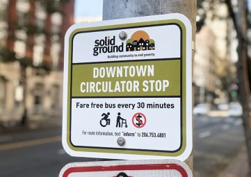 A Downtown Circulator sign on 1st Ave. It reads "Fare free bus every 30 minutes. For route information, text 'inform' to 206.753.4801"