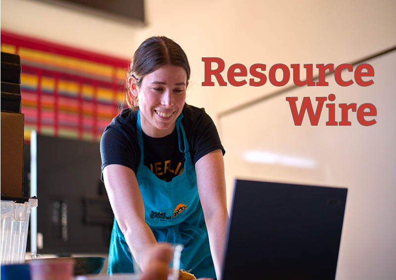 A woman with dark hair pulled back in a ponytail and a teal-colored apron faces a laptop and smiles. The words "Resource Wire" appear next to her.
