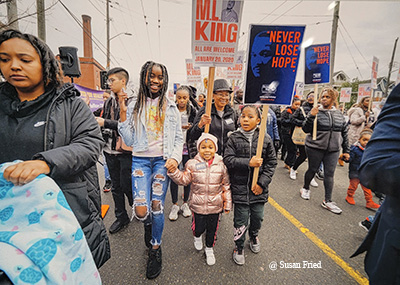 Three girls smile while walking with other marchers in a MLK march in 2020.