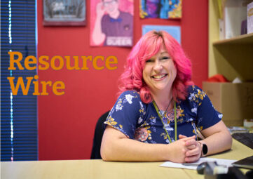 A woman with hair dyed bright pink smiles at the camera from her desk. The words "Resource Wire" appear beside her.