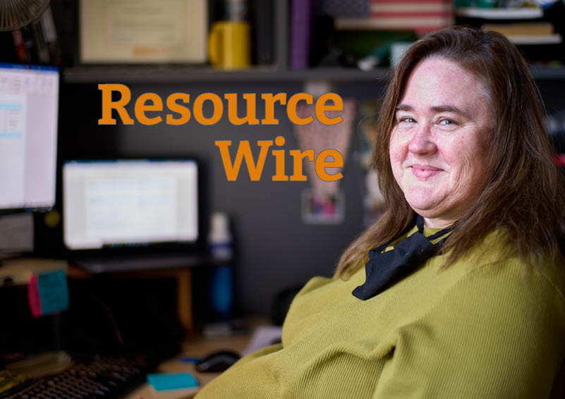 A woman in an office cubicle with two computer monitors lean back in her chair and smiles. The words "Resource Wire" appear beside her.