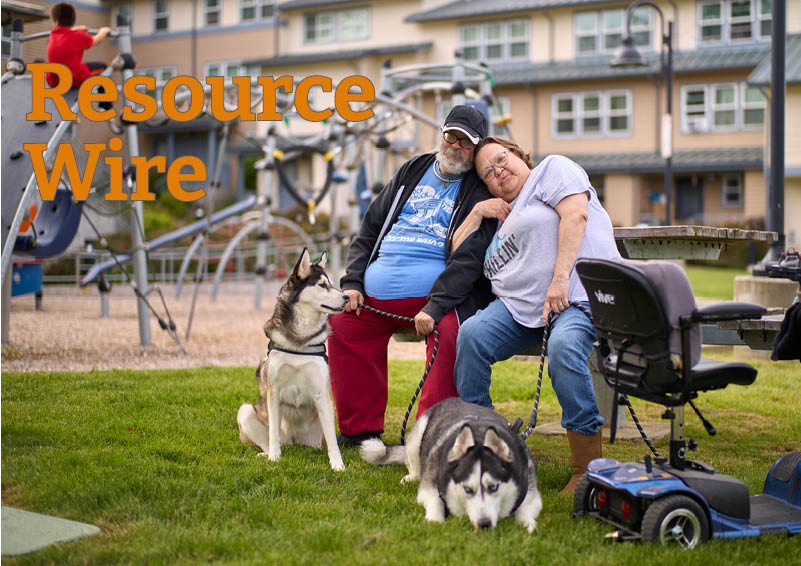 A man and woman sitting on a picnic bench and leaning into each other as their two huskies look on. The words "Resource Wire" appears beside them.