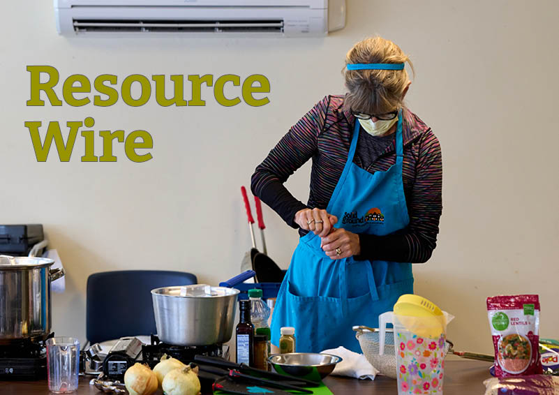 A woman in a blue apron stands in front of a table filled with cooking equipment and ingredients. The words Resource Wire appear beside her.