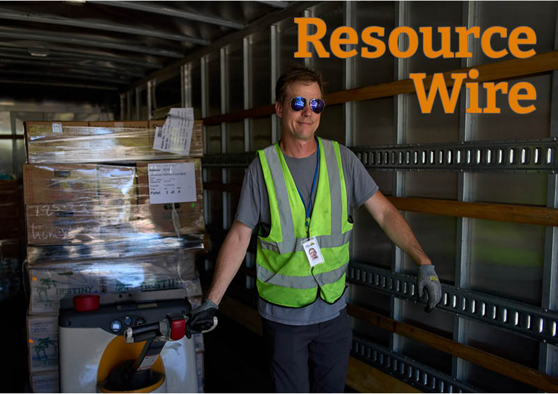A man in a bright green safety vest and sunglasses moves a pallet of packaged food from inside a truck trailer. The words "Resource Wire" appear above him.