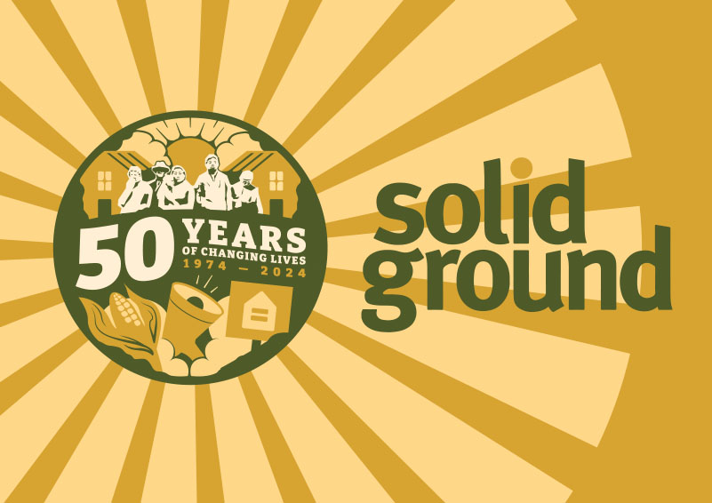 Solid Ground commemorative logo on a golden sunburst background with a circular dark green, peach and ivory graphic. It has silhouettes of several people in front of a pair of houses. The sun is shining from between two clouds. Text reads "50 years of changing lives, 1974-2024." Under the words are illustrations of an ear of corn, a megaphone, and a protest sign showing an equals symbol inside the outline of a house.