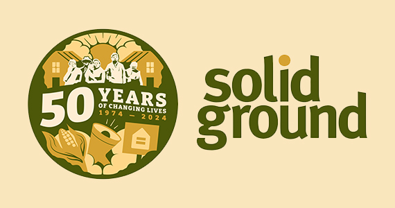 Solid Ground commemorative logo on a beige background with a circular dark green, peach and ivory graphic. It has silhouettes of several people in front of a pair of houses. The sun is shining from between two clouds. Text reads "50 years of changing lives, 1974-2024." Under the words are illustrations of an ear of corn, a megaphone, and a protest sign showing an equals symbol inside the outline of a house.
