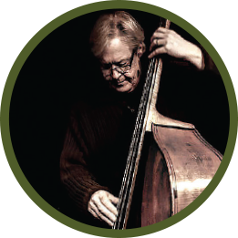 Circular photo with a forest-green frame of a white man with greying hair and glasses playing upright bass. He's wearing all black.