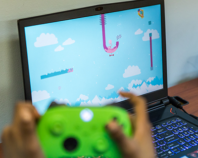 A close up shot of a video game on a laptop screen with a child's game on controller out of focus in the foreground.
