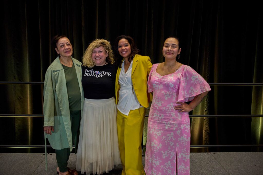 Four women in fancy dress pose for a photo.