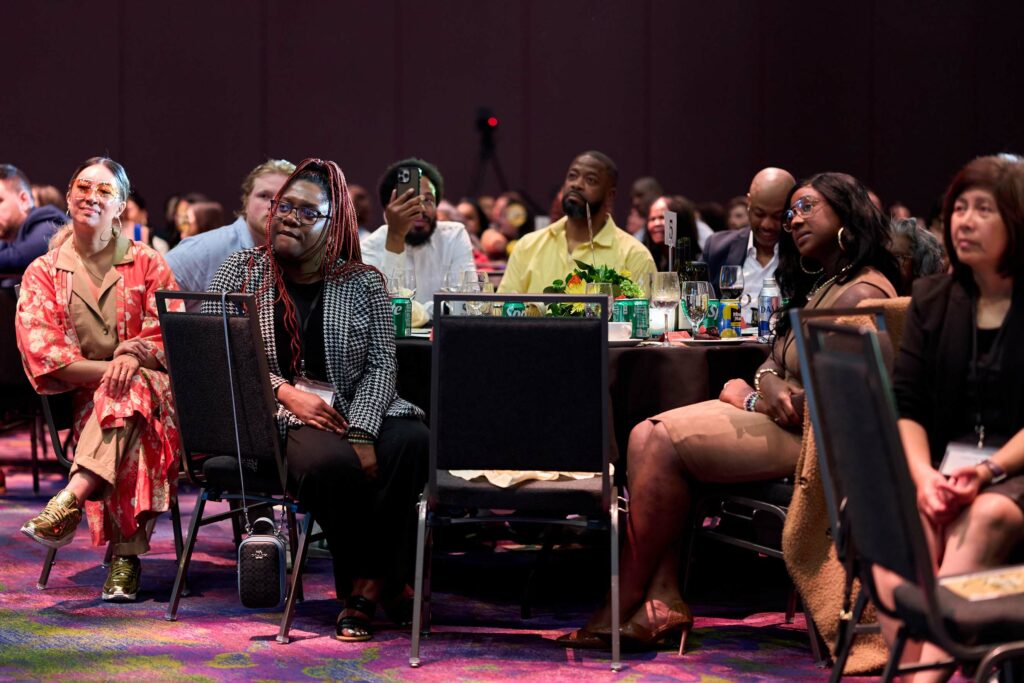 A group of people seated around a table attentively watching something out of frame.