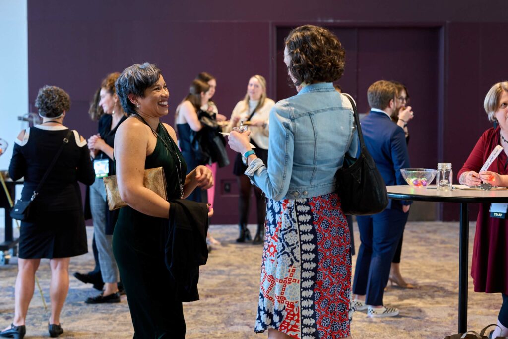 Two women smile and talk at a fancy reception.