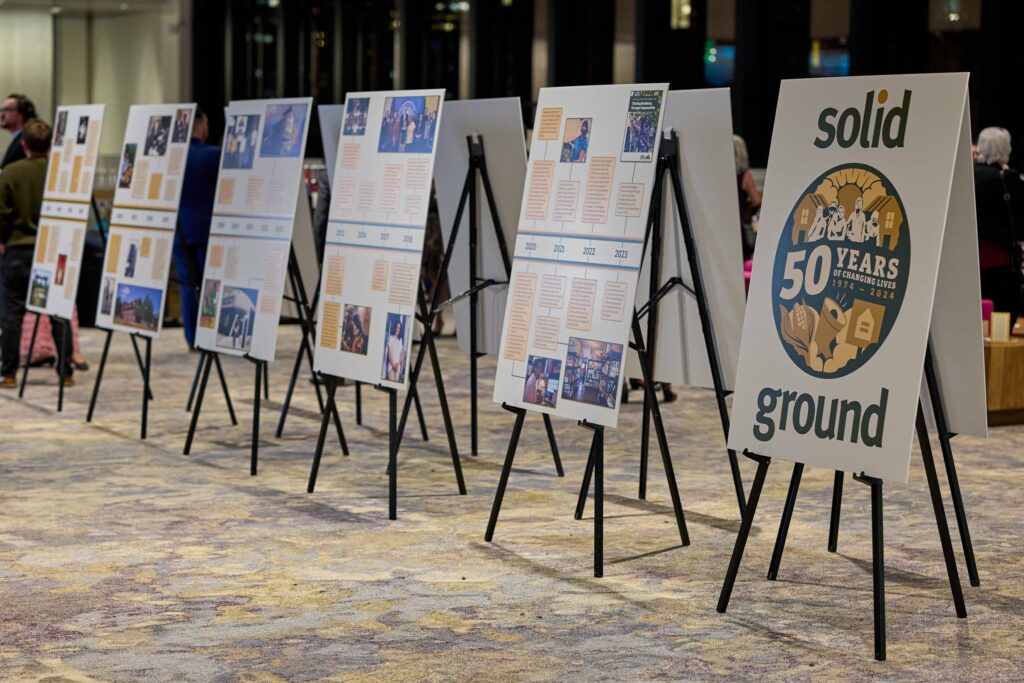 Several posters on easels. One says "50 years" and "solid Ground"