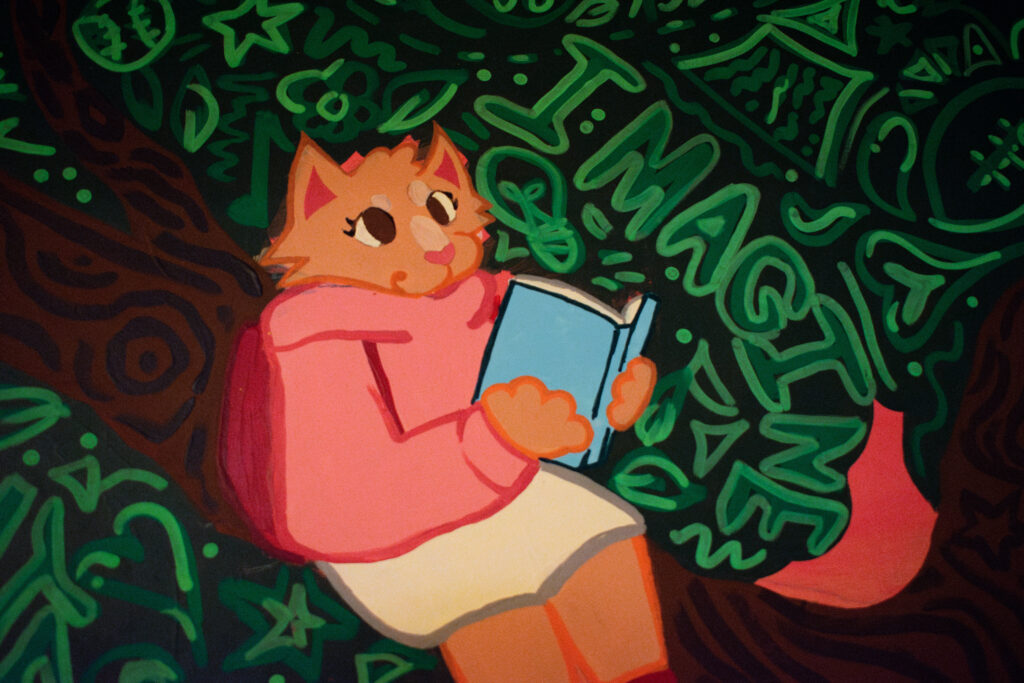 A close up of one of the cartoon characters in the mural, a cat sitting in the tree reading a book.